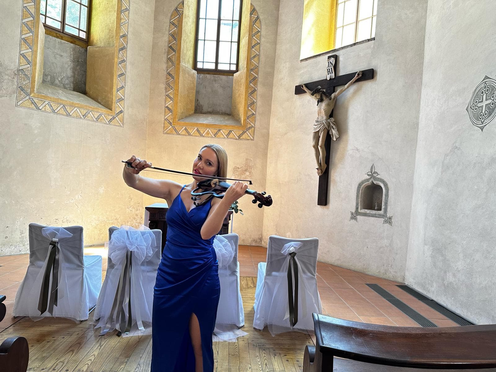 Glasba za cerkveni poročni obred — violinistka z violino v modri obleki med nastopom v cerkveni kapeli